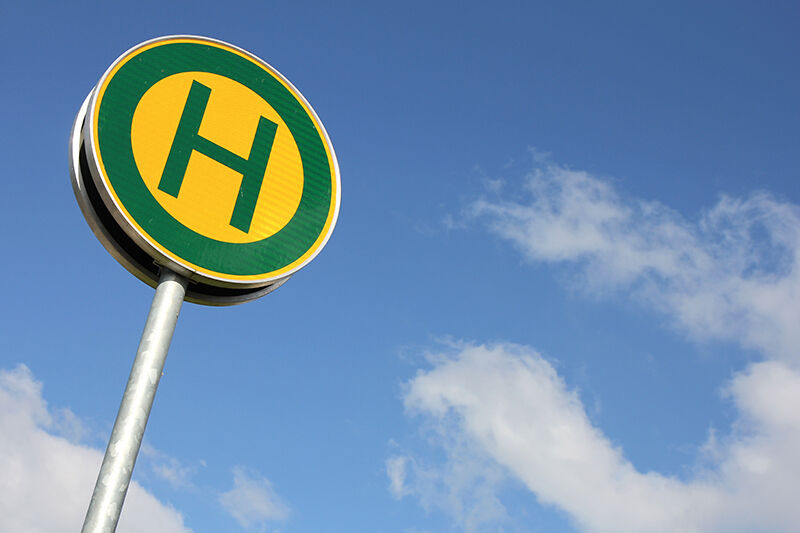 Anreise mit öffentlichen Verkehrsmitteln, Haltestellenschild und blauem Himmel